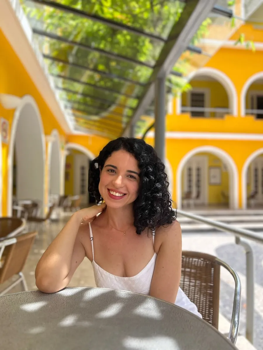 Millena Barreto sorrindo em um pátio ensolarado