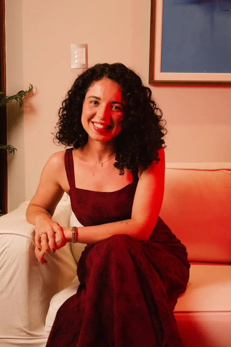 Millena Barreto sorrindo, sentada em um sofá