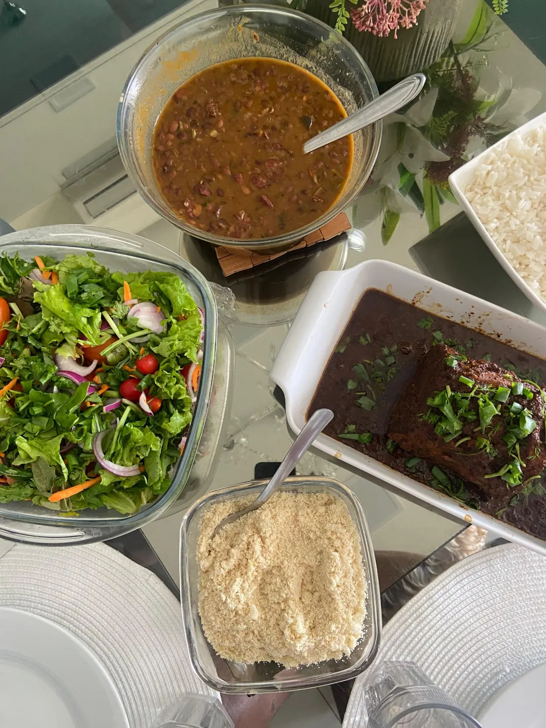 Mesa de almoço com feijão, arroz, salada, farofa e carne assada