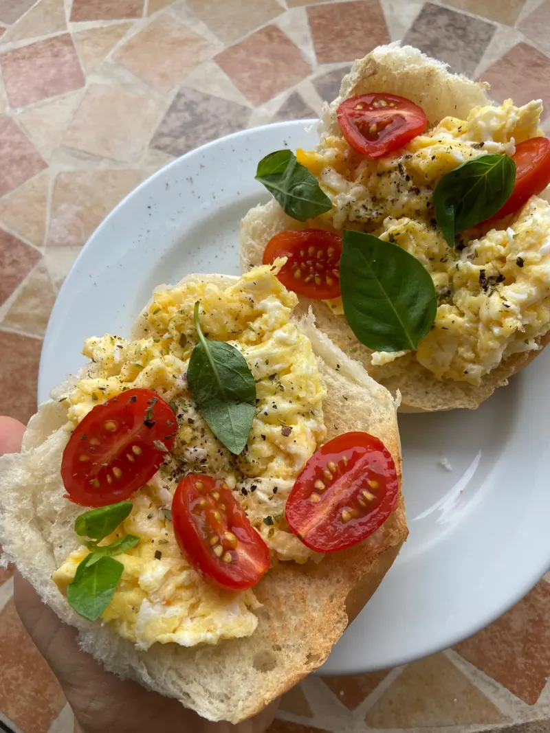 Pão com ovos mexidos, tomate-cereja e manjericão